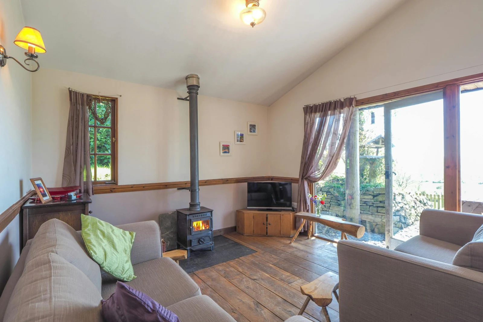 Living area with sofas, log burner, tv, doors to garden