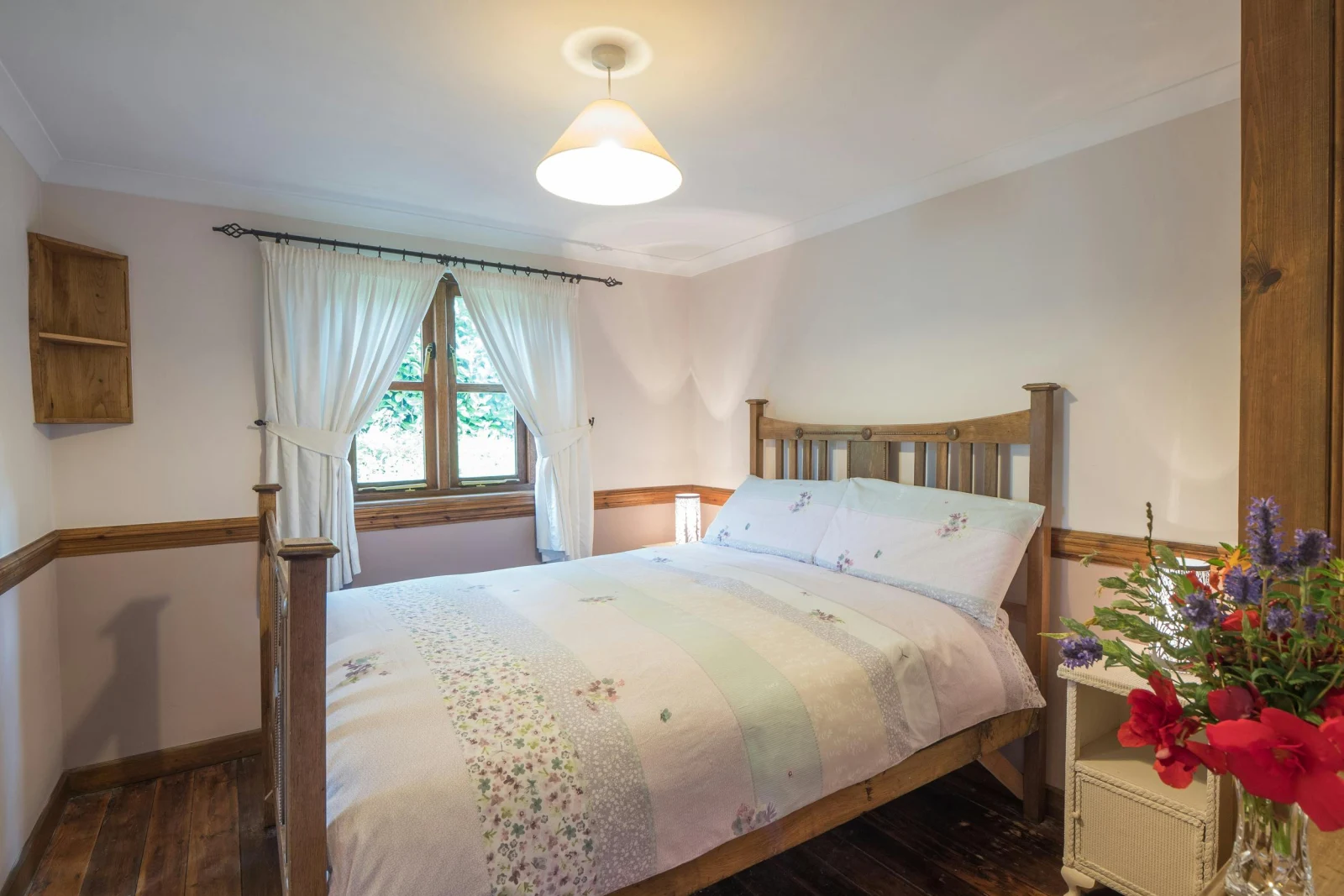 Double bed, with beside tables and lamps and a vase of flowers