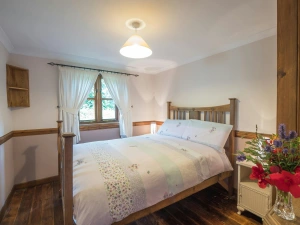 Double bed, with beside tables and lamps and a vase of flowers