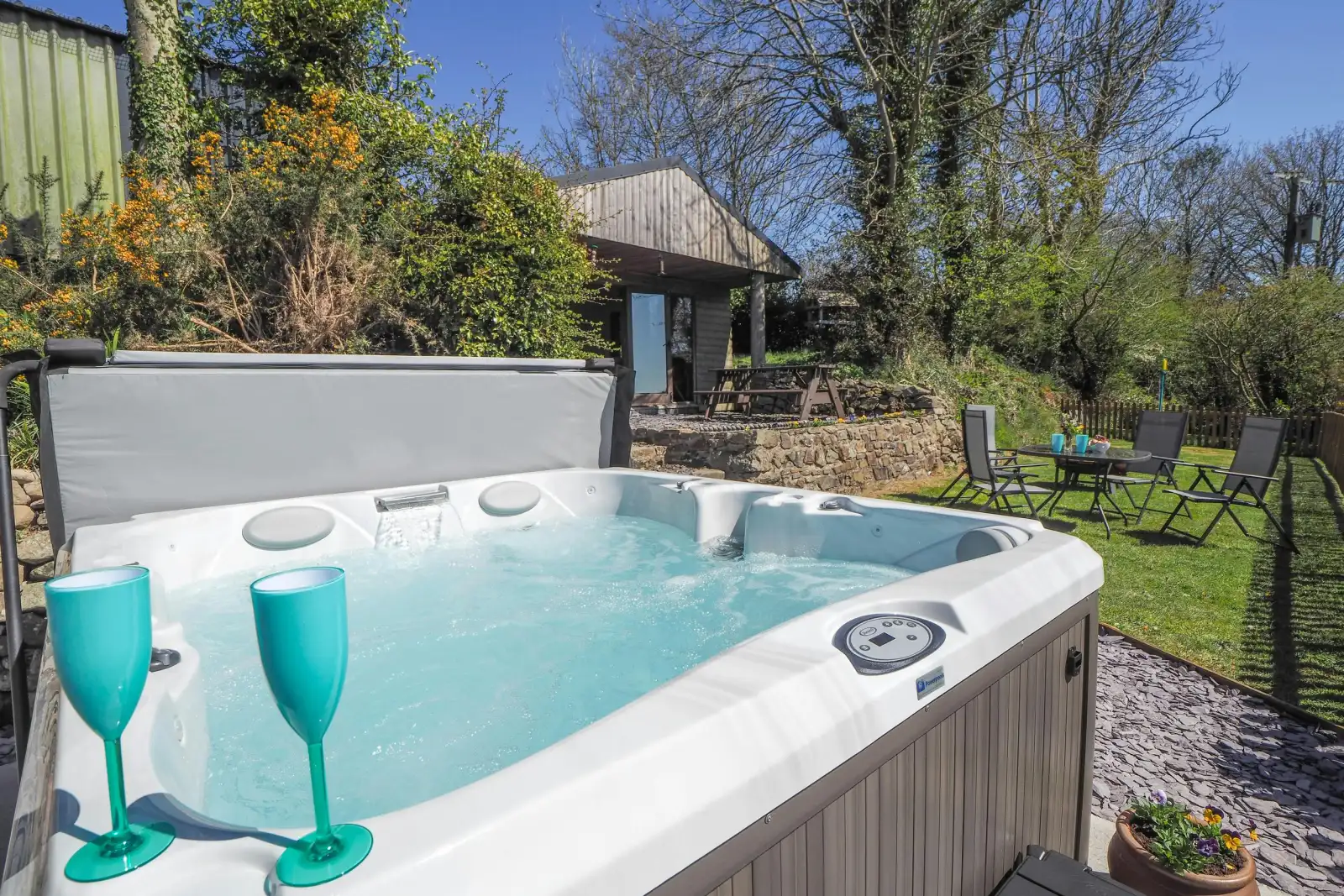 Caban Cynnes hot tub with two blue wine glasses and lawn in background