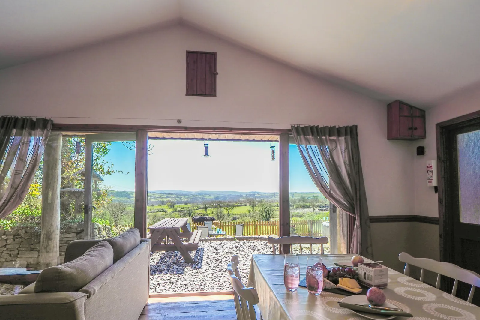 Dining area with table and chairs, double doors leading to patio with picnic bench