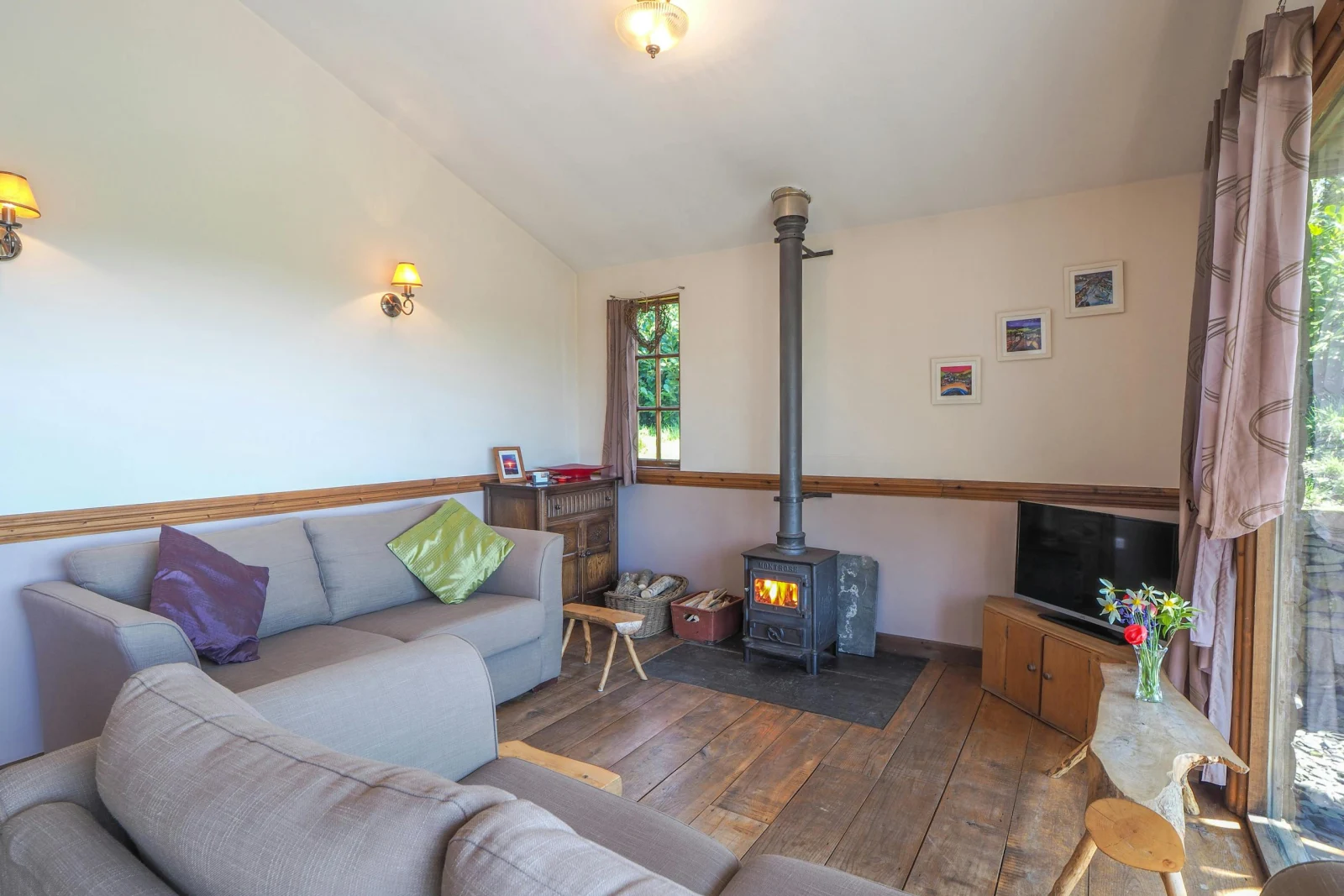 Lounge area with log burner, two sofas, tv, double doors open to garden