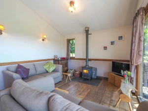 Lounge area with log burner, two sofas, tv, double doors open to garden