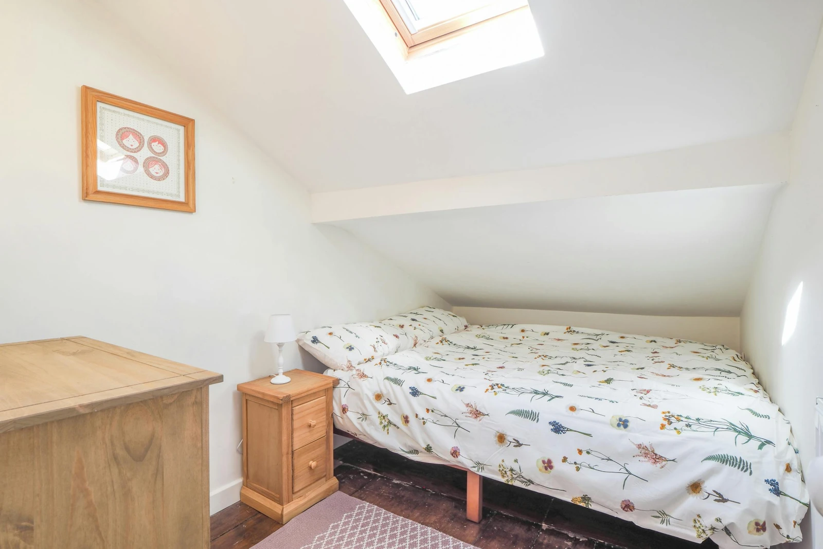 Double bed, bedside cabinet and lamp, low ceiling on one side