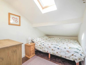 Double bed, bedside cabinet and lamp, low ceiling on one side