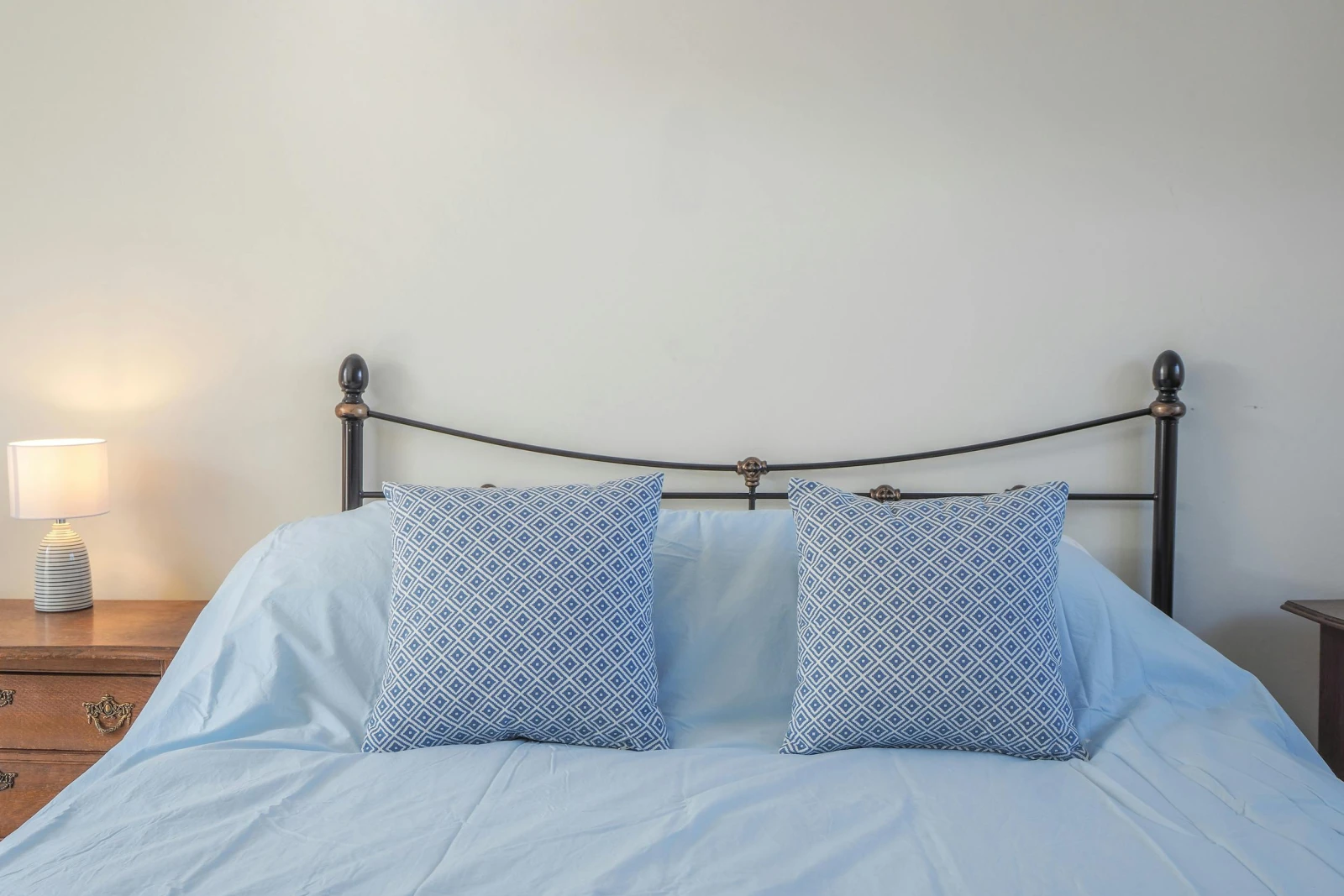Kind size bed, bedside cabinet and lamp, cushions on the bed
