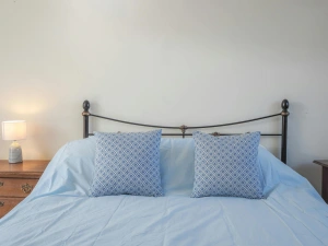 Kind size bed, bedside cabinet and lamp, cushions on the bed