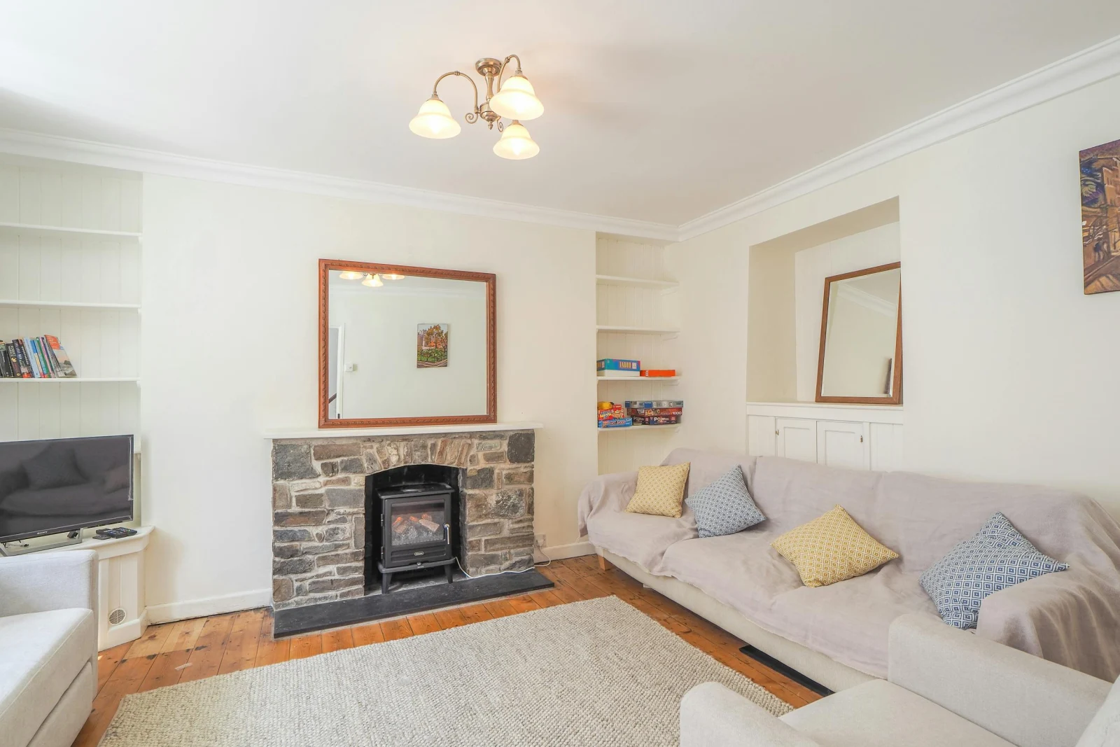 Fireplace, mirror above, sofas, TV, shelves in the alcoves