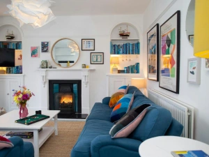 Sitting room with large blue sofa and colourful cushions. Coffee Table