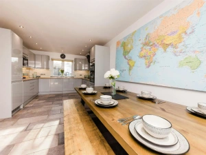 Map of the world on the wall, table and benches laid for lunch with kitchen in background
