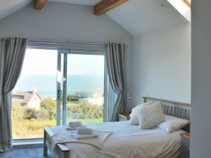 kingsize bed with bedside table and lamp. Patio doors with views to sea
