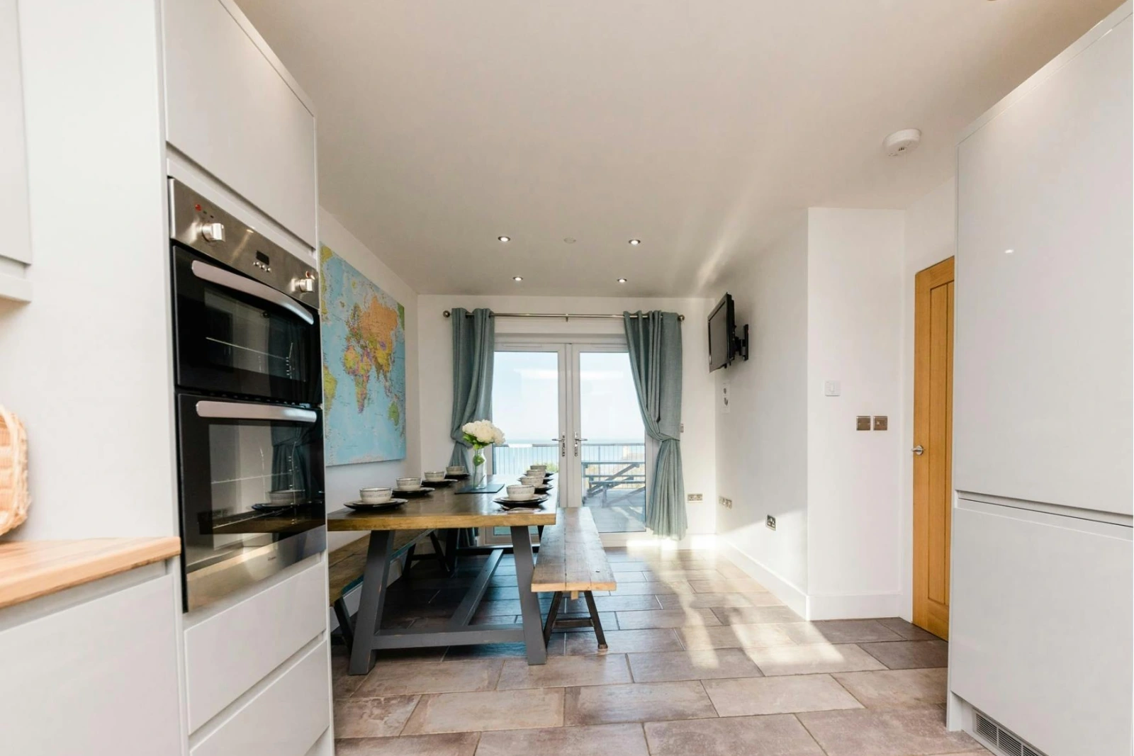 Kitchen leading into the dining room with table and chairs and doors leading to the patio