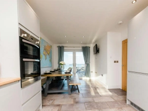 Kitchen leading into the dining room with table and chairs and doors leading to the patio