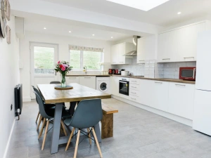 kitchen with dining table, matching cupboard units and appliances.
