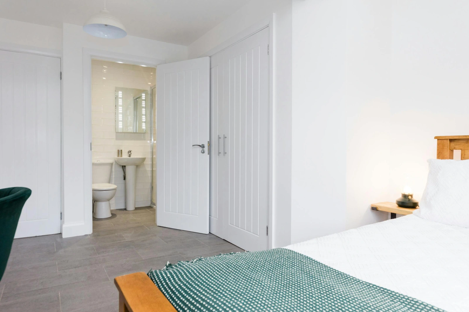 Master bedroom with laminated flooring and bedside lamp.