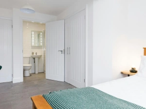 Master bedroom with laminated flooring and bedside lamp.