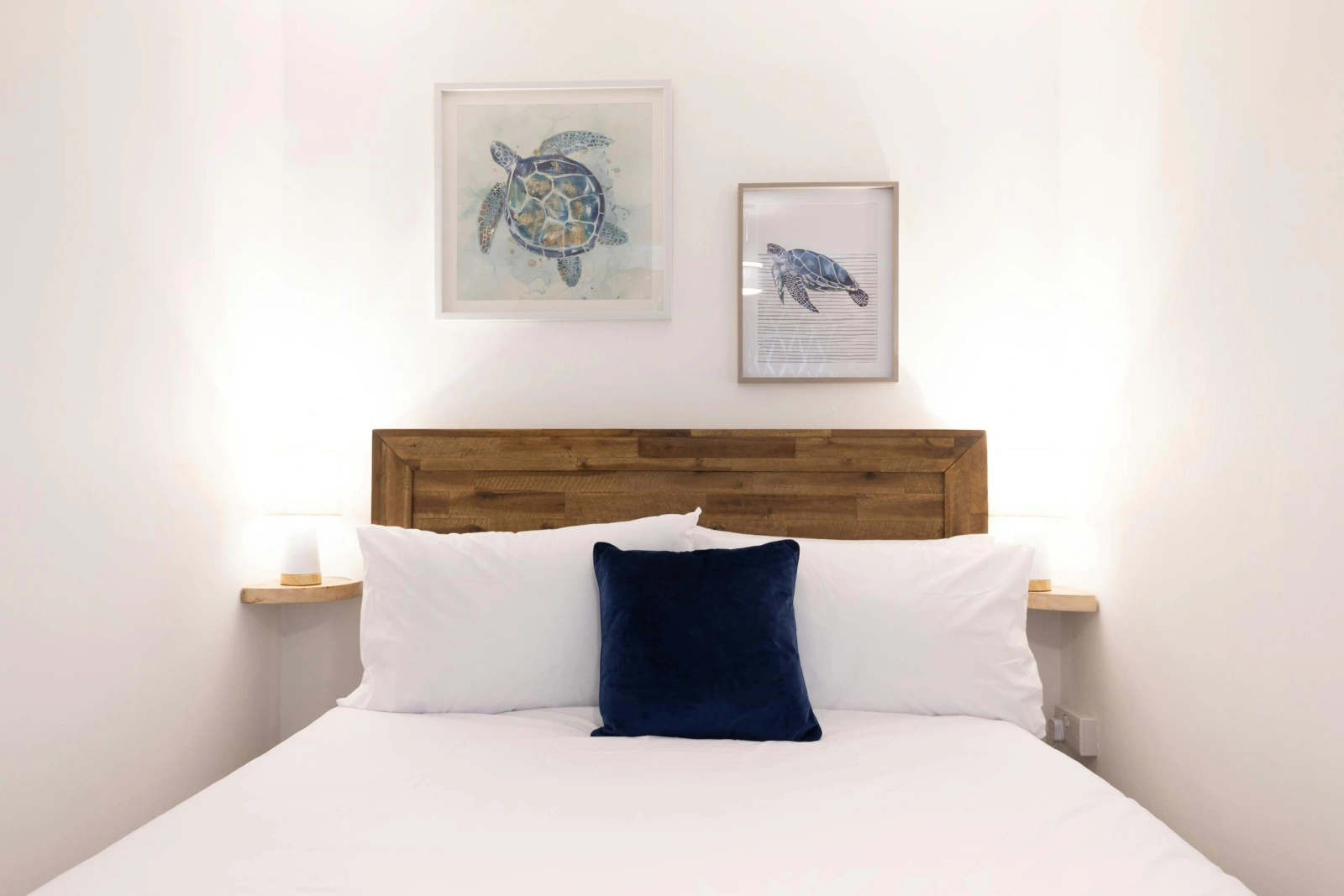 Bedroom with double bed, photo frames on the wall, side table and light.