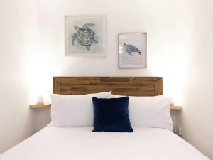 Bedroom with double bed, photo frames on the wall, side table and light.