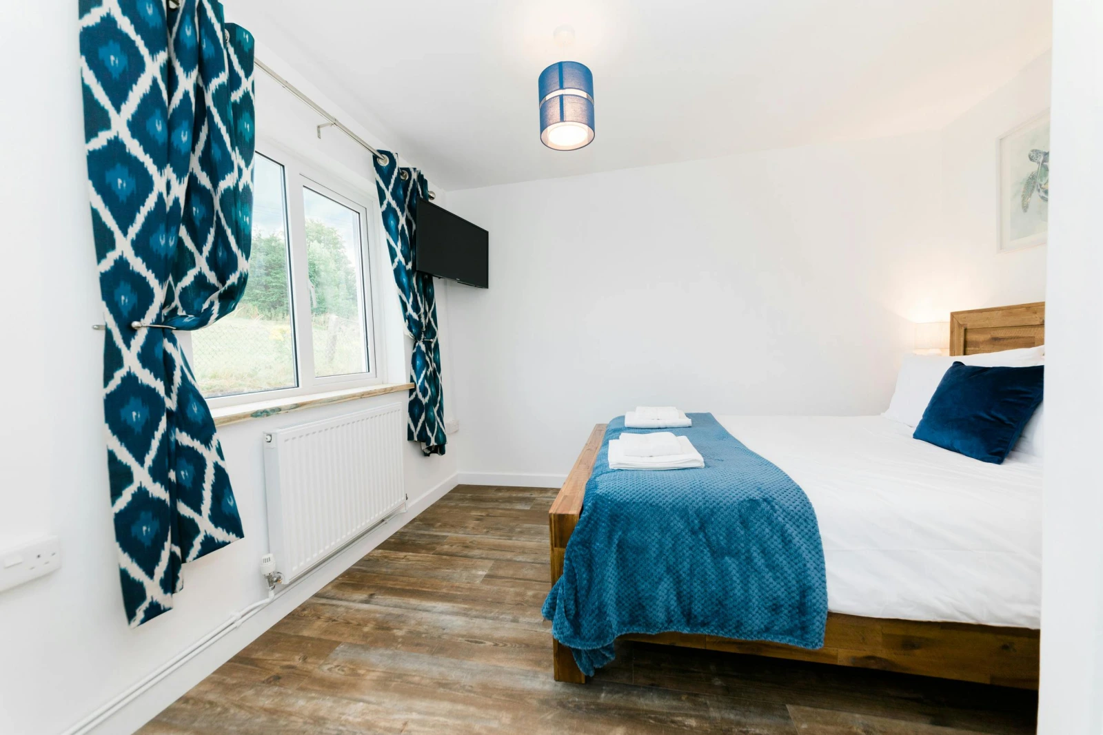 Bedroom with laminated wood flooring and wall mounted central heater.