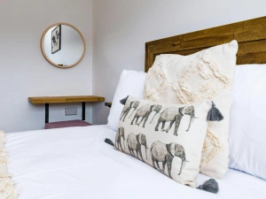 Bedroom with laminated wood flooring, single bed, wall mirror, desk and chair.
