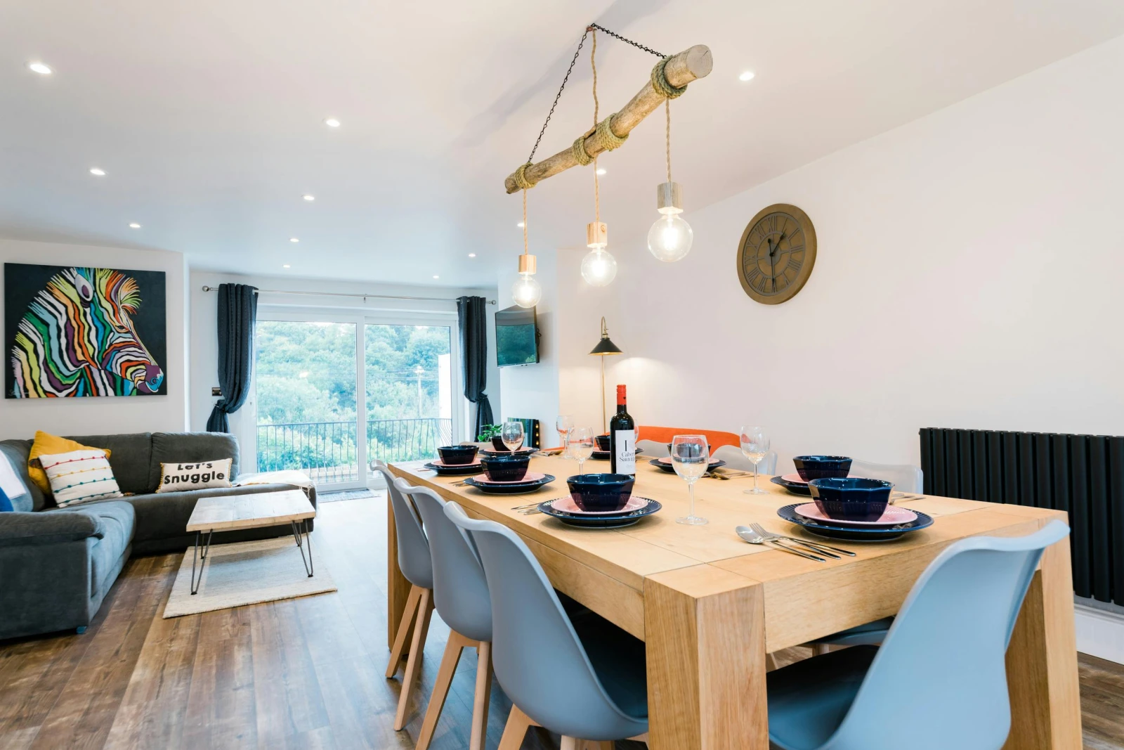Living room with laminated flooring and tv. Dining table in-between the kitchen and living room.