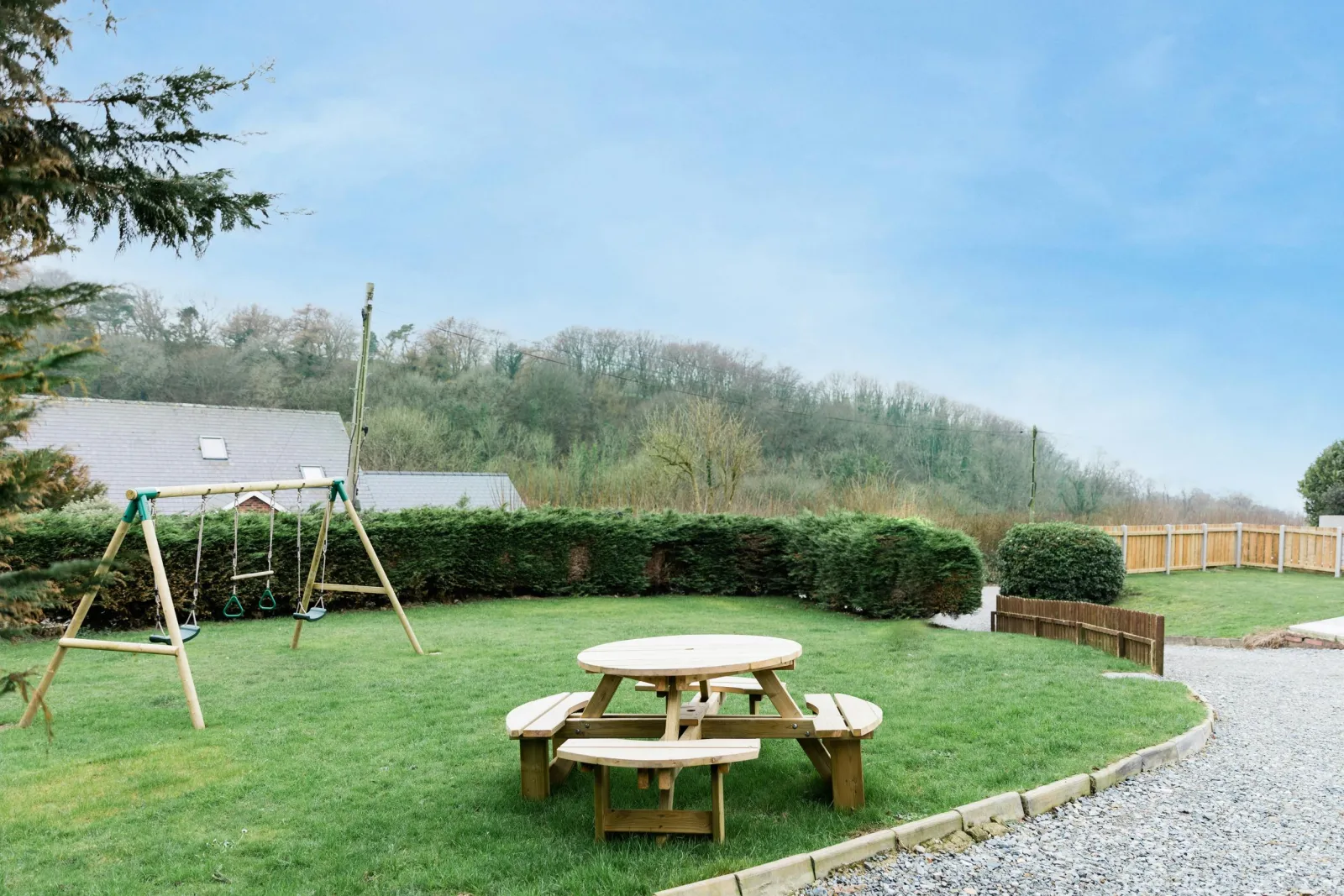 Kids swing set and picnic bench on the grass at the front of the property.