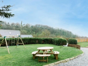 Kids swing set and picnic bench on the grass at the front of the property.