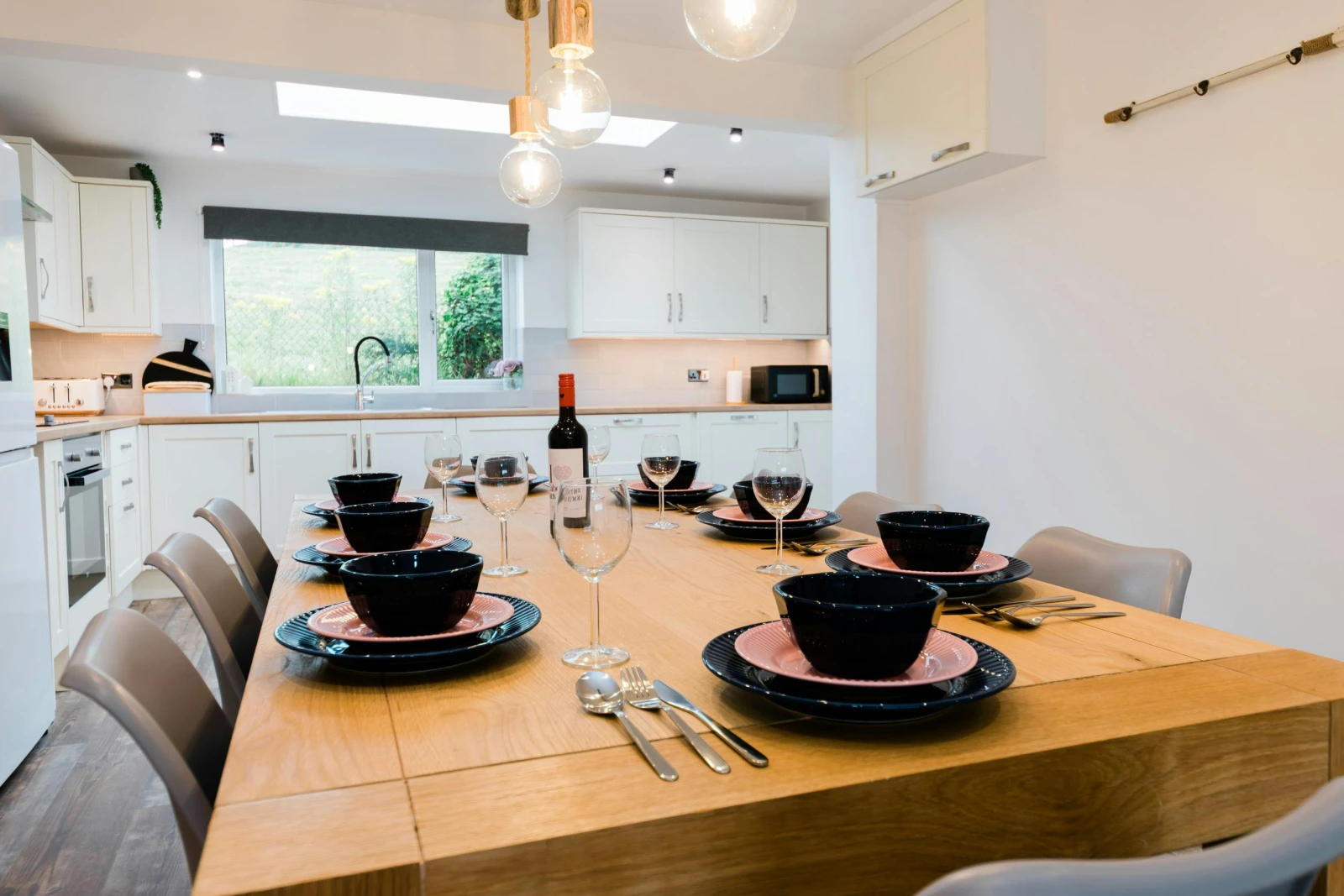 Large wooden dining table in the kitchen. matching bowls and plates on top.