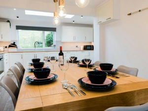 Large wooden dining table in the kitchen. matching bowls and plates on top.
