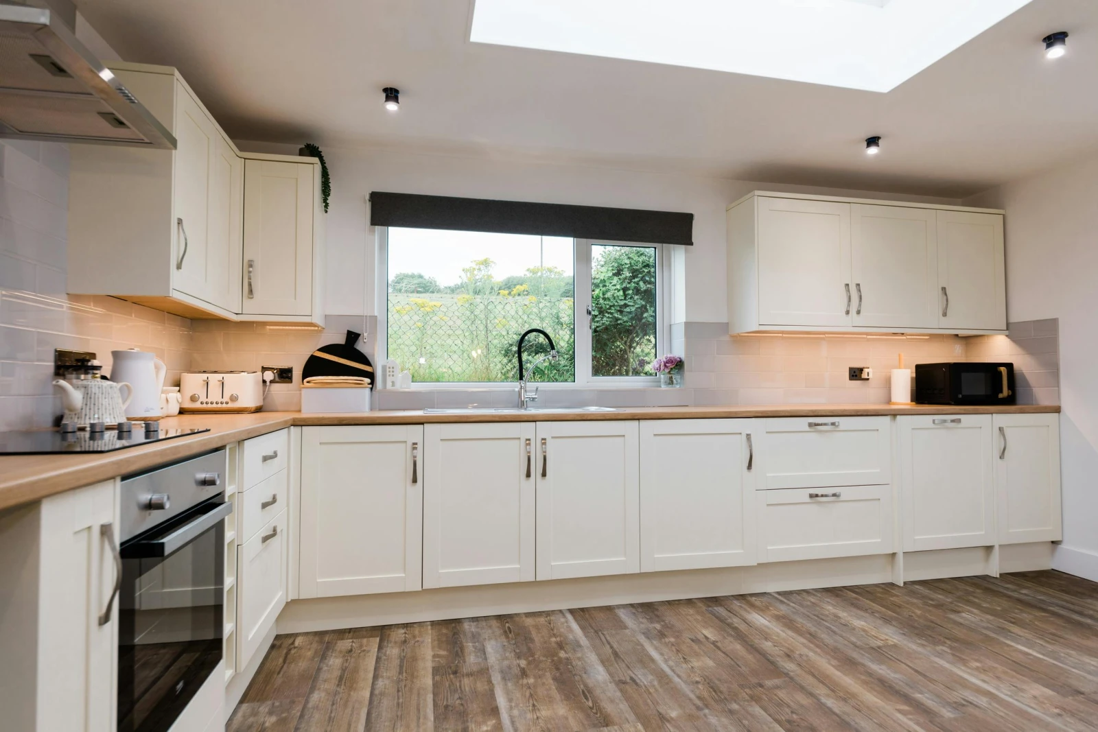 Kitchen with white cupboards, integrated cooker, toaster and microwave.
