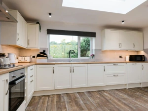 Kitchen with white cupboards, integrated cooker, toaster and microwave.
