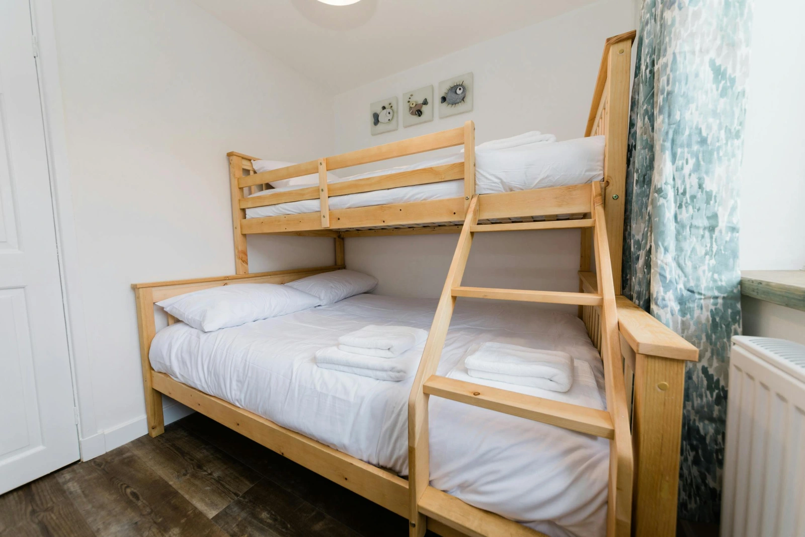 Twin bedroom with wooden bunk bed and wall heater.