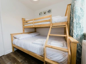 Twin bedroom with wooden bunk bed and wall heater.