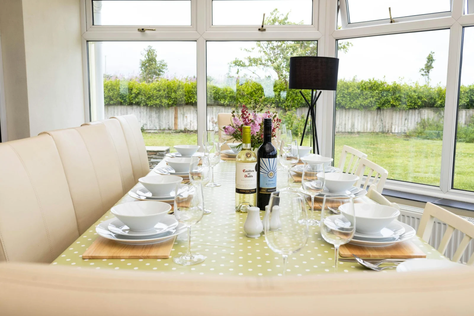 Dining table in the conservatory, laid with plates, wine glasses and wine