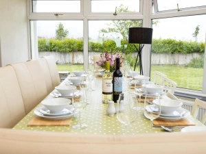 Dining table in the conservatory, laid with plates, wine glasses and wine