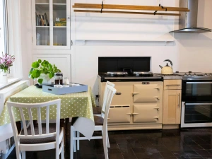 The kitchen with the aga, a table and 3 chairs with a slate floor
