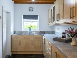 The kitchen with a selection of cupboard, a workspace with a tray of coffee and a bunch of flowers