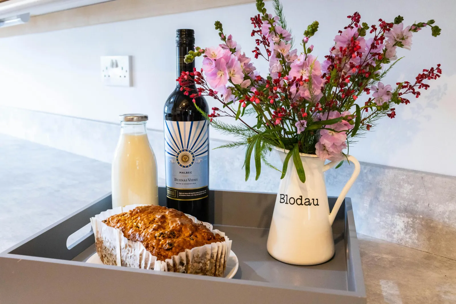 A tray in the kitchen with wine, milk and flowers