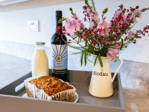 A tray in the kitchen with wine, milk and flowers