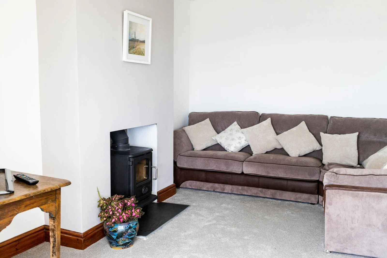 The lounge with a corner sofa, log burner and a carpet floor