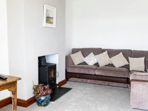 The lounge with a corner sofa, log burner and a carpet floor