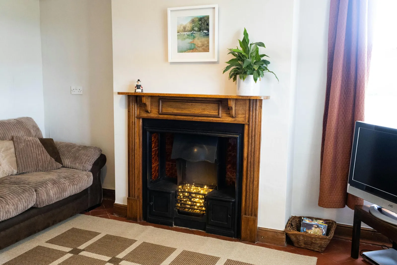 The second lounge, with sofa, fireplace, television. Wooden floor with a rug.