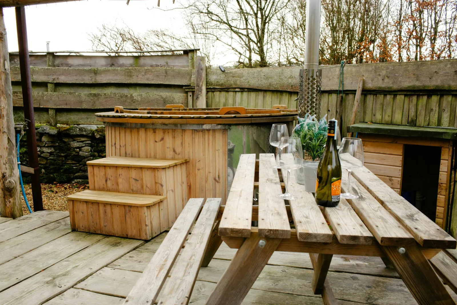Hot tub with steps. Picnic bench with glasses and a bottle of wine on