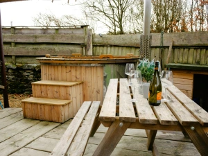 Hot tub with steps. Picnic bench with glasses and a bottle of wine on