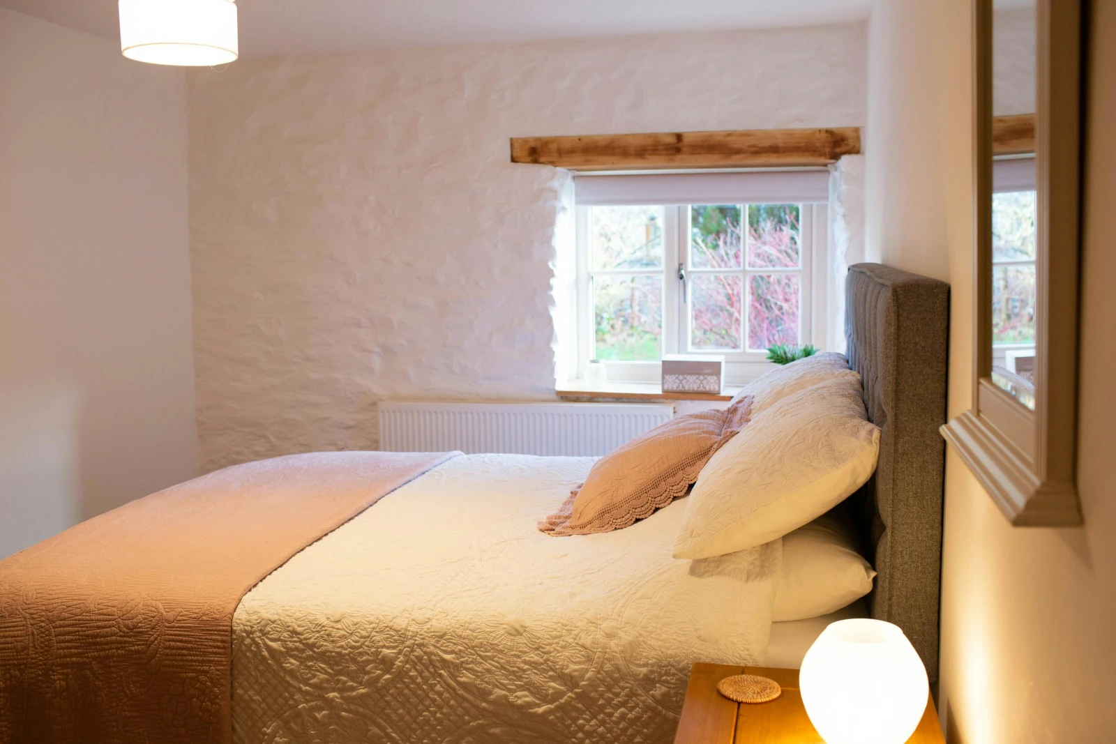 Bedside tables and lamps. Wall mounted mirror. Window with views of the garden