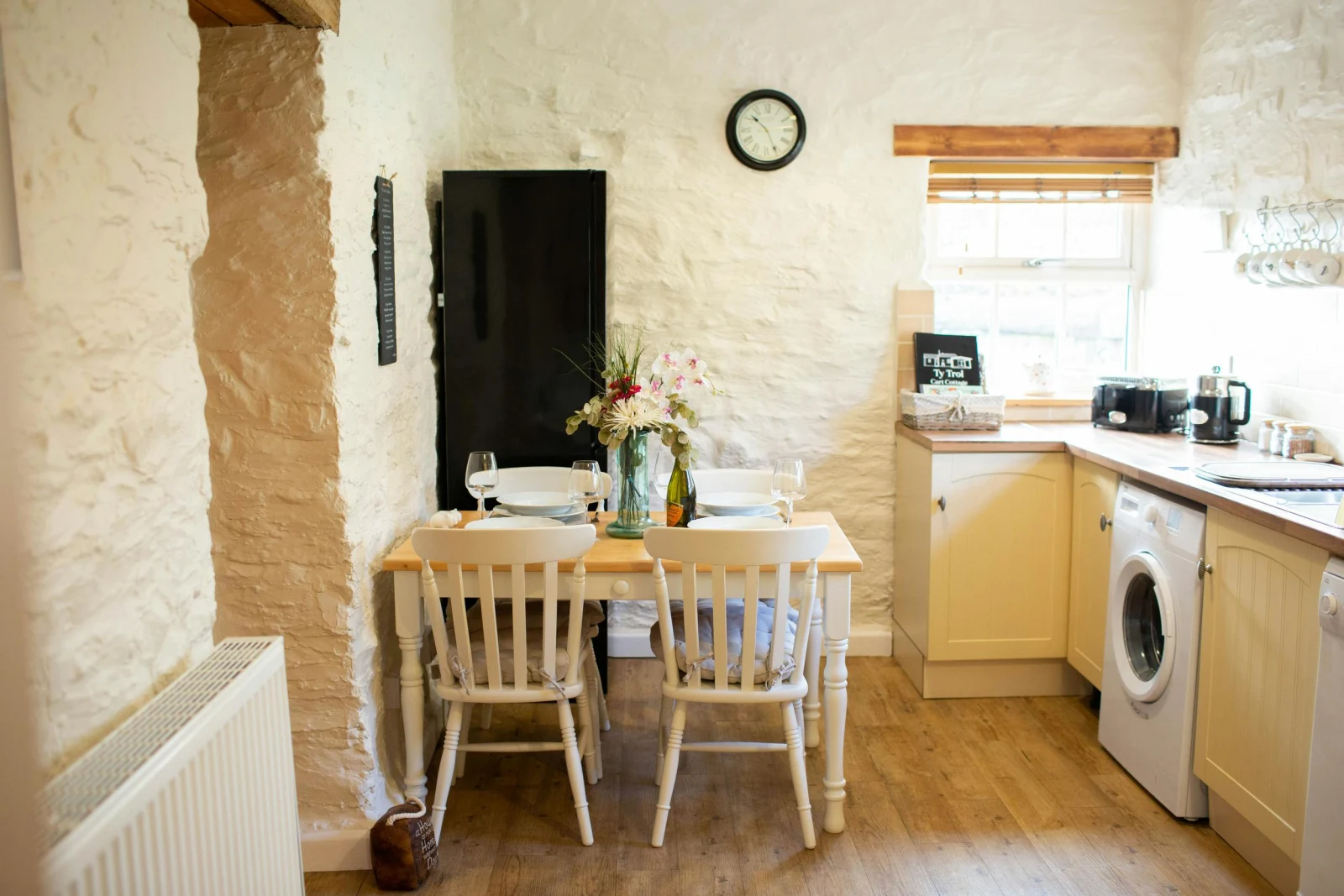 Washing machine. Cream coloured base cupboards. Table and four chairs