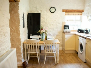 Washing machine. Cream coloured base cupboards. Table and four chairs