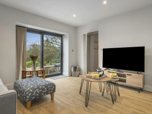 Living room with sofa, patterned ottoman, coffee table and TV on a wooden stand
