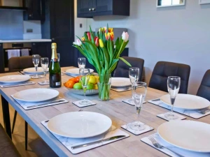 Dining table set with plates, cutlery and glasses, with tulips and fruit in the centre