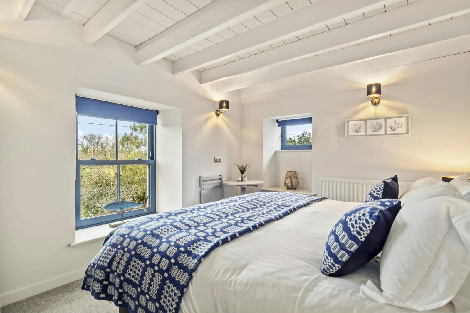 White bedroom with double bed and blue patterned throw